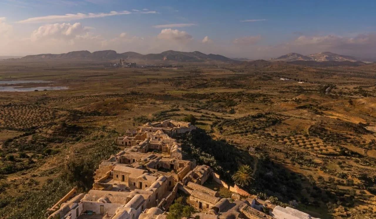 An old hilltop village above olive groves and plains in evening light