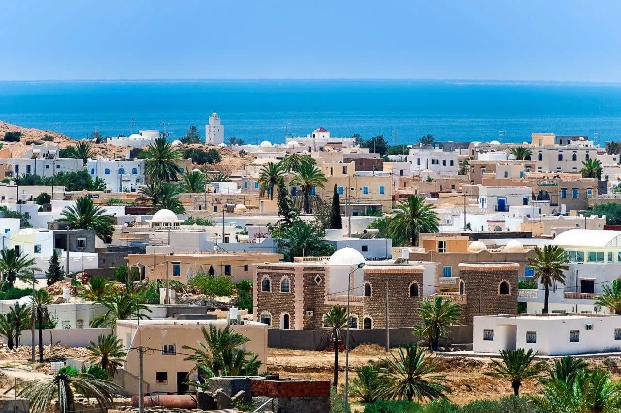 A white town among palm trees running down to the sea