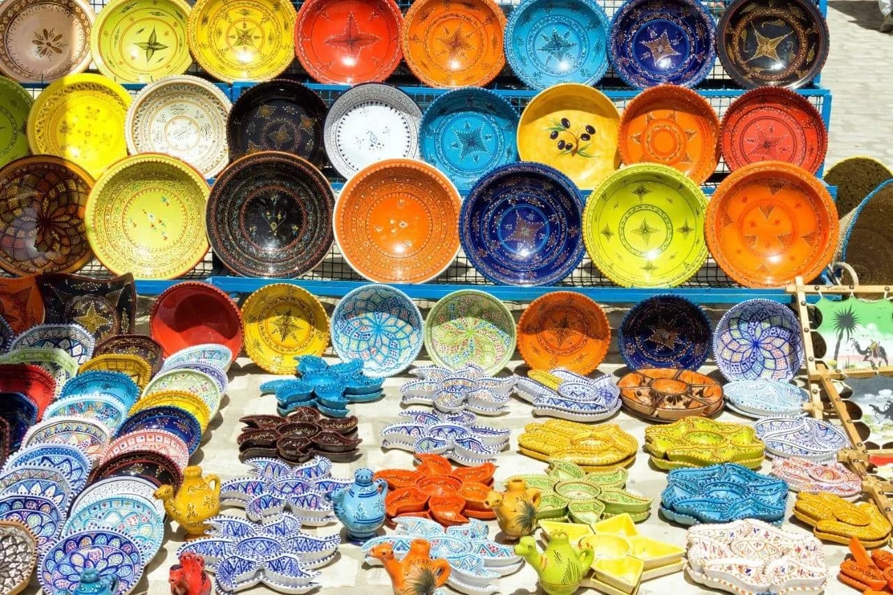 Stacks of brightly painted ceramic bowls and plates at a market stall