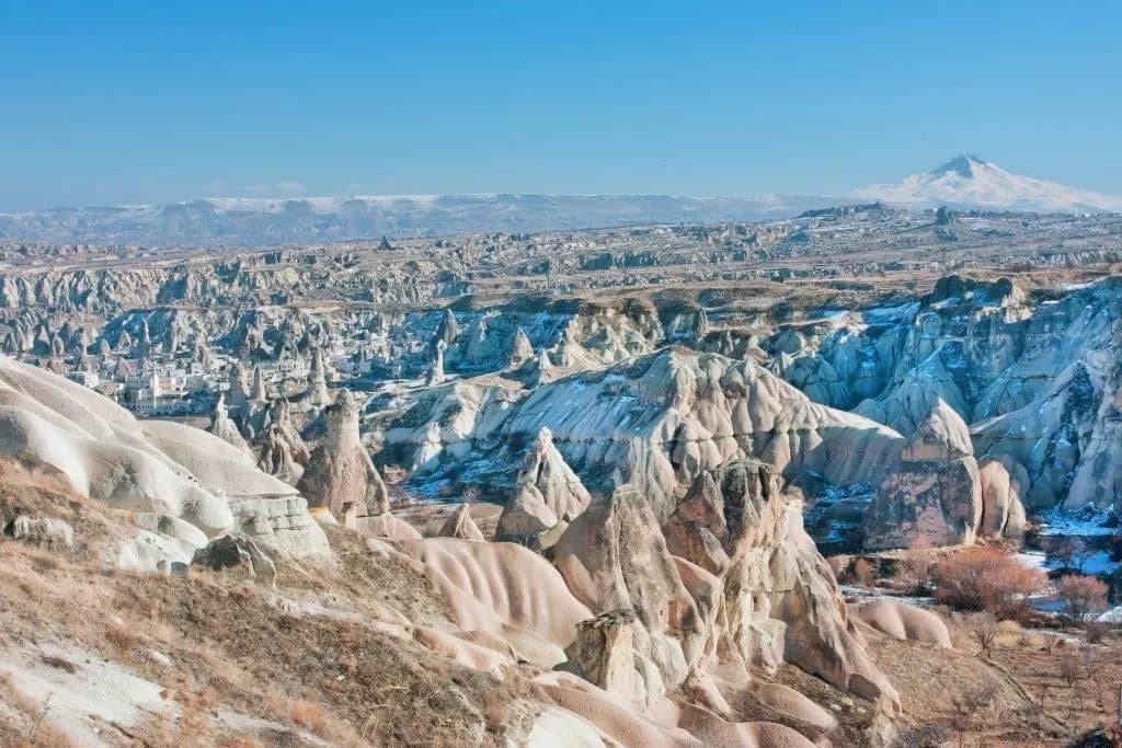 Pale rock valleys of Cappadocia with a snowy peak on the horizon
