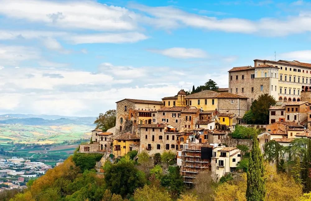 Stone houses on the edge of an Umbrian hill town above the valley