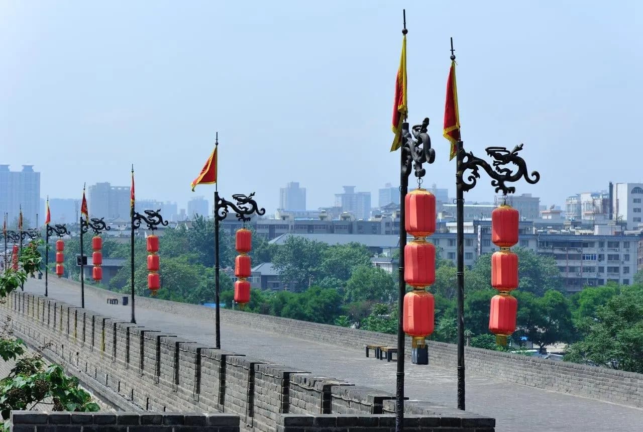 Red lanterns and flags lining the top of the city wall