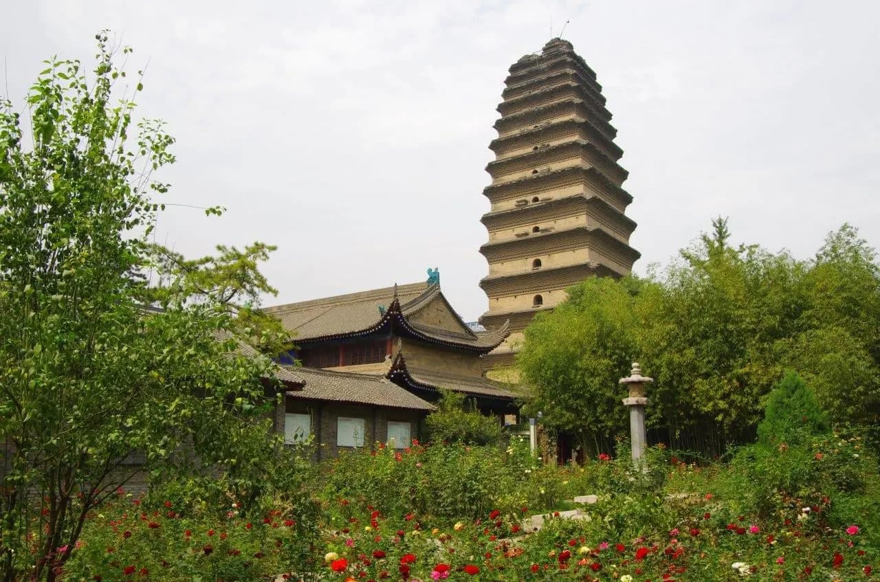 A slender pagoda rising behind temple roofs and a garden