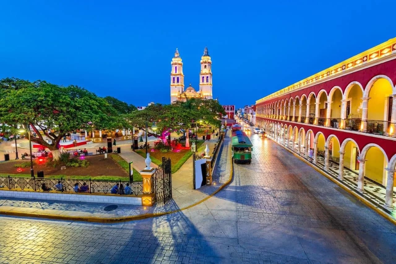 The cathedral and arcaded square of Campeche lit up at dusk