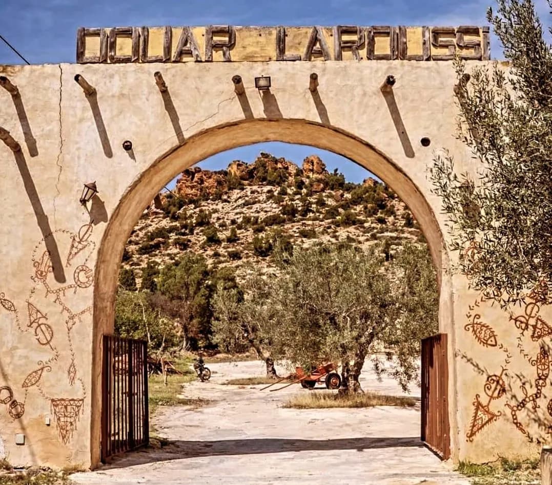 The arched gateway into Douar Laroussi with rocky hills beyond