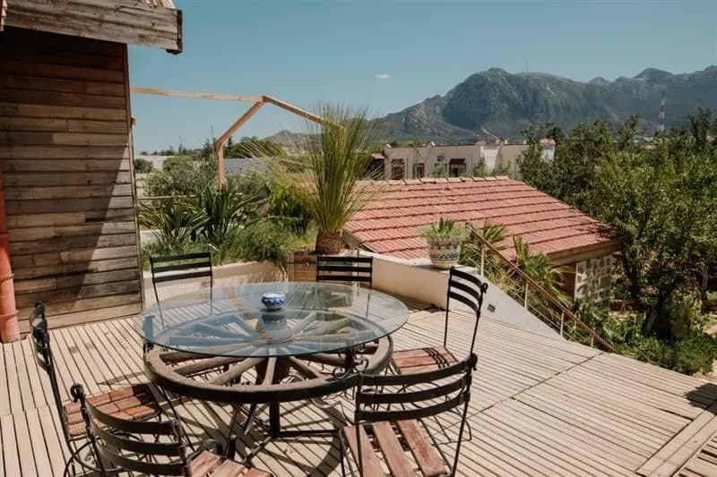 A wooden terrace with a table and chairs looking towards the Zaghouan mountains