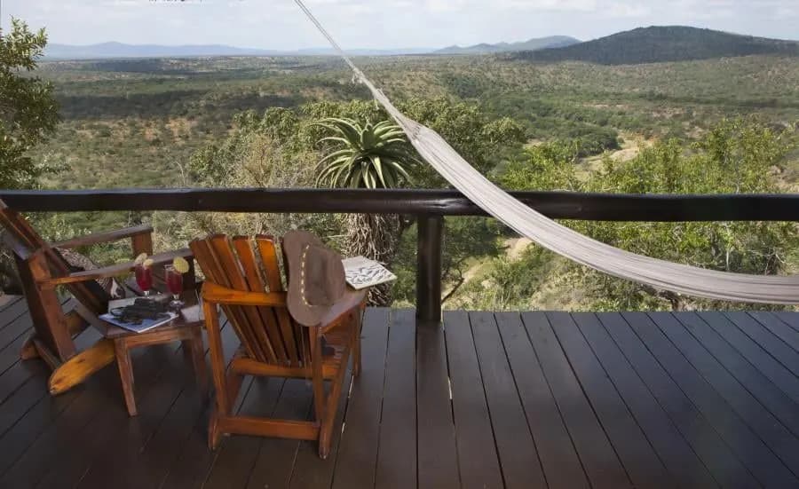 A timber deck with chairs and a hammock looking over the Zululand bush