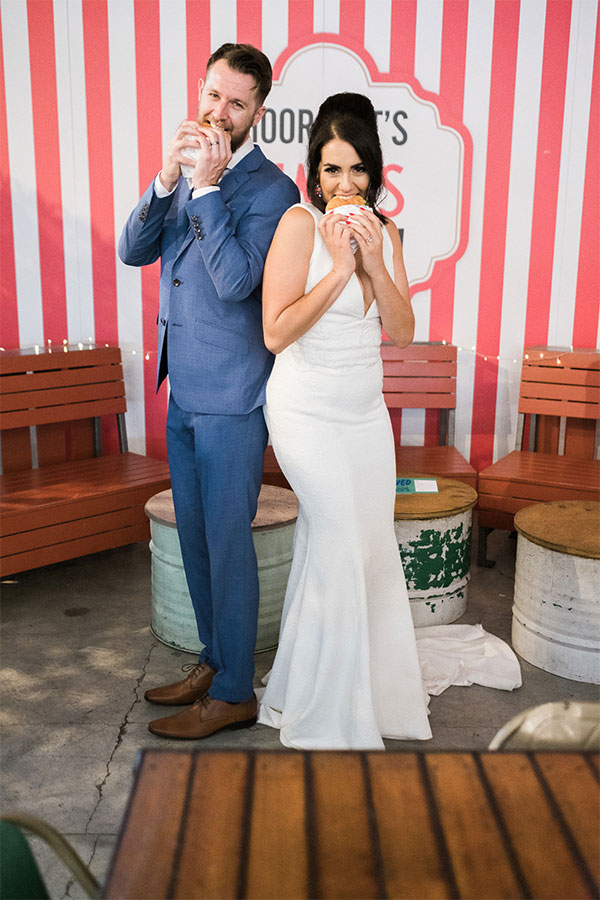 bride and groom eating burgers in their wedding clothes