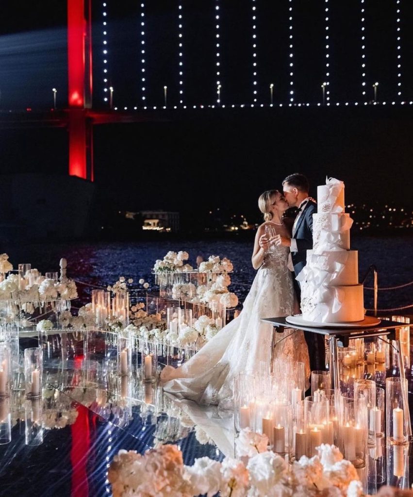 Romantic reception venue adorned with white flowers and candles with the Bosphorus bridge in Türkiye
