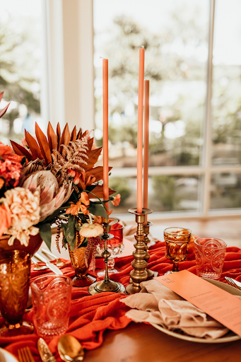 Rust colored candles, mantel, and flowers, gives a pop of color to the tablescape
