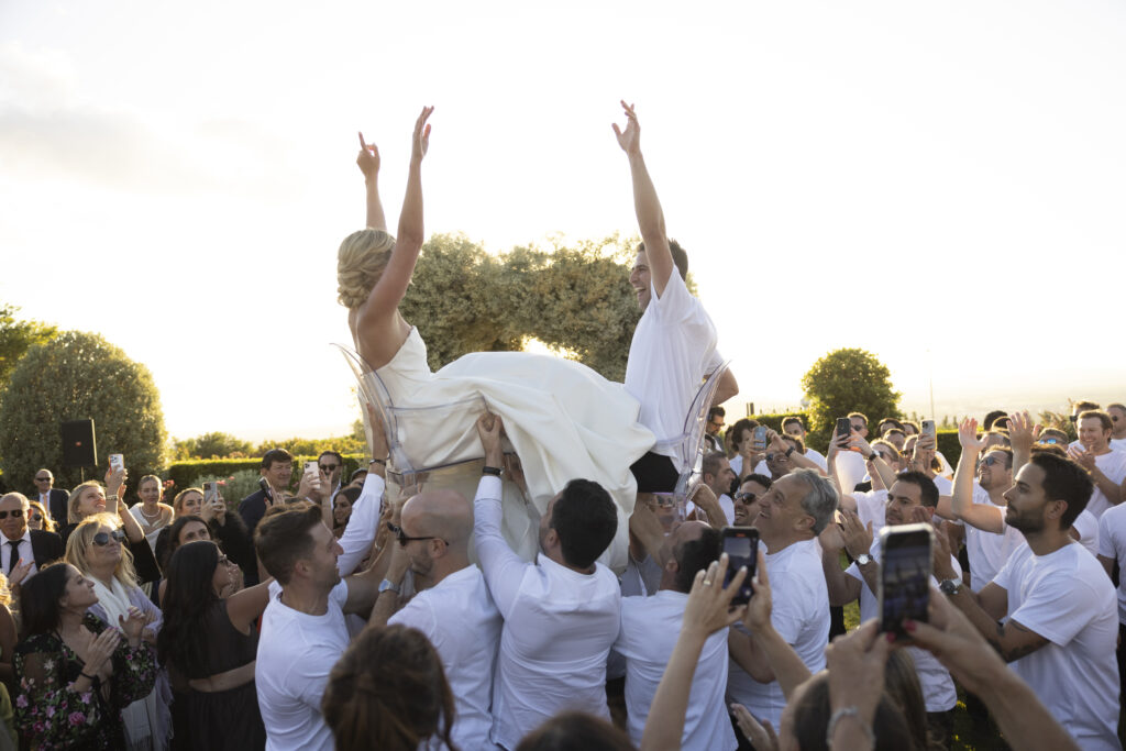 Bride and groom lifted into the air by their guests
