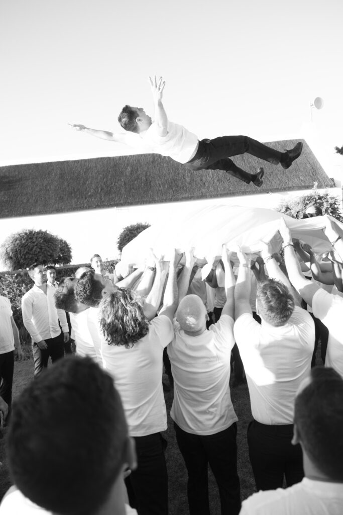 Happy guests throw the groom into the air