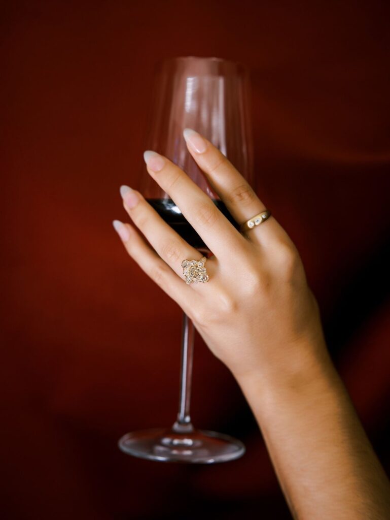 A vintage ring featured while holding a wine glass.