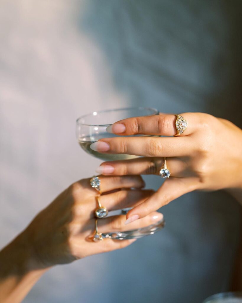 Multiple beautiful vintage engagement rings while making holding a glass.