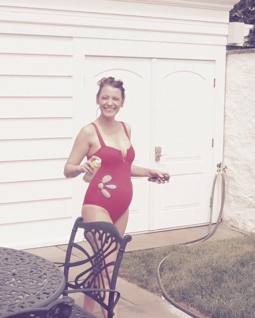 Blake Lively in all smiles while showing off her baby bump in a red one-piece swimsuit.