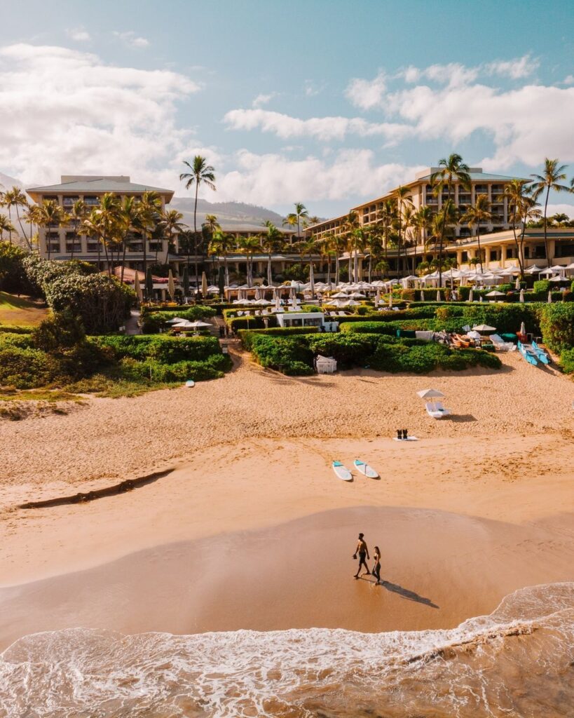 Couple strolling by the beach of one of the luxury honeymoon resorts in Hawaii, Four Seasons Resort Maui at Wailea.