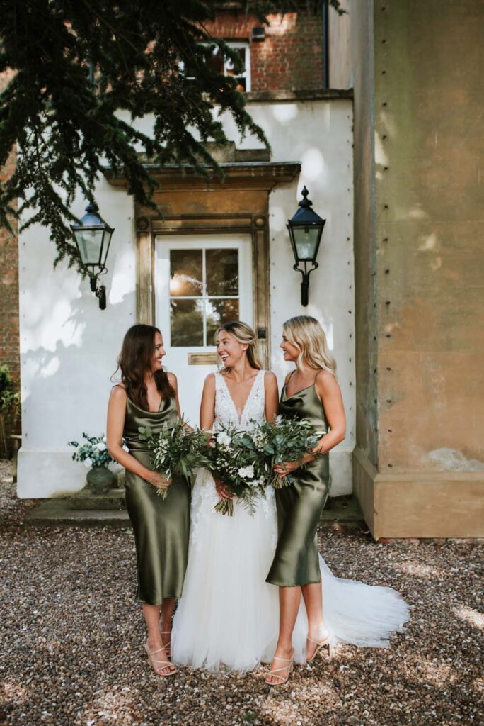 The bride and her bridesmaids in sage green dresses.