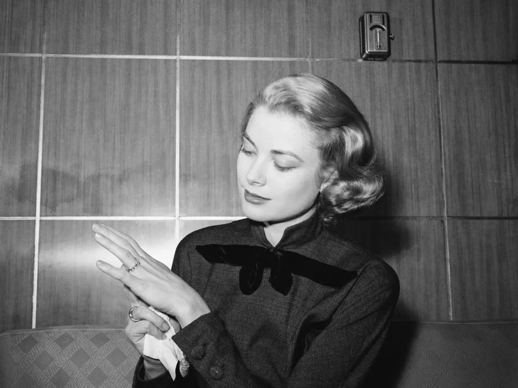 Woman admiring diamond ring on her hand, showcasing luxury and elegance, set against a stylish backdrop, reflecting opulence associated with high-value jewelry.