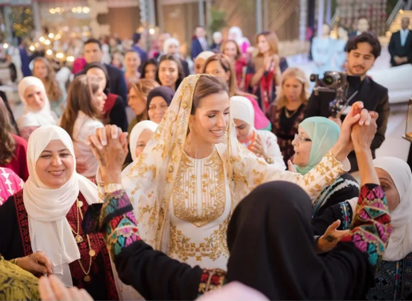 Bride celebrating during Henna Night surrounded by women, traditional attire, joyful atmosphere, cultural wedding rituals.