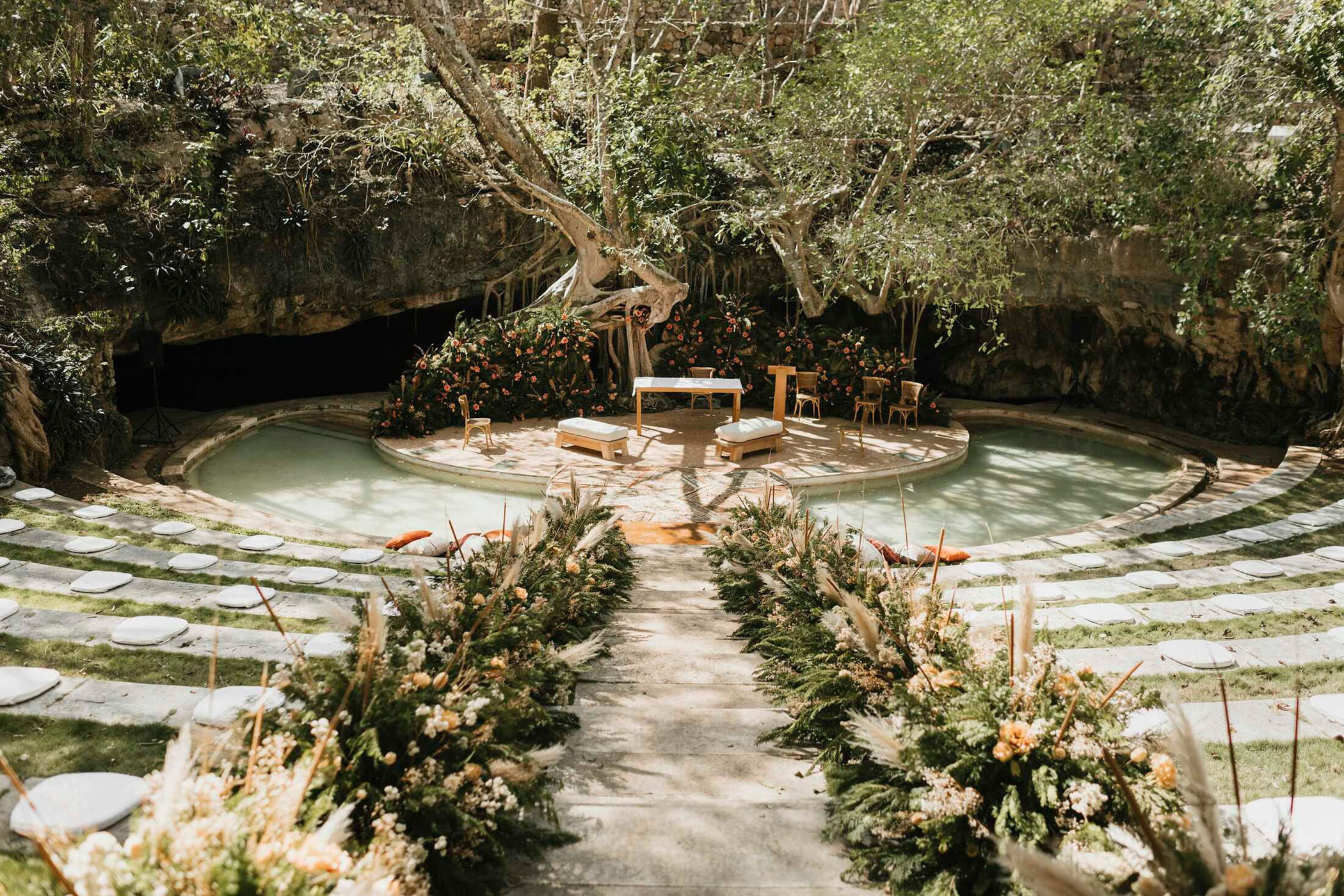 Outdoor wedding venue in Mexico featuring a circular altar surrounded by lush greenery, floral arrangements, and seating areas, ideal for luxury destination weddings.