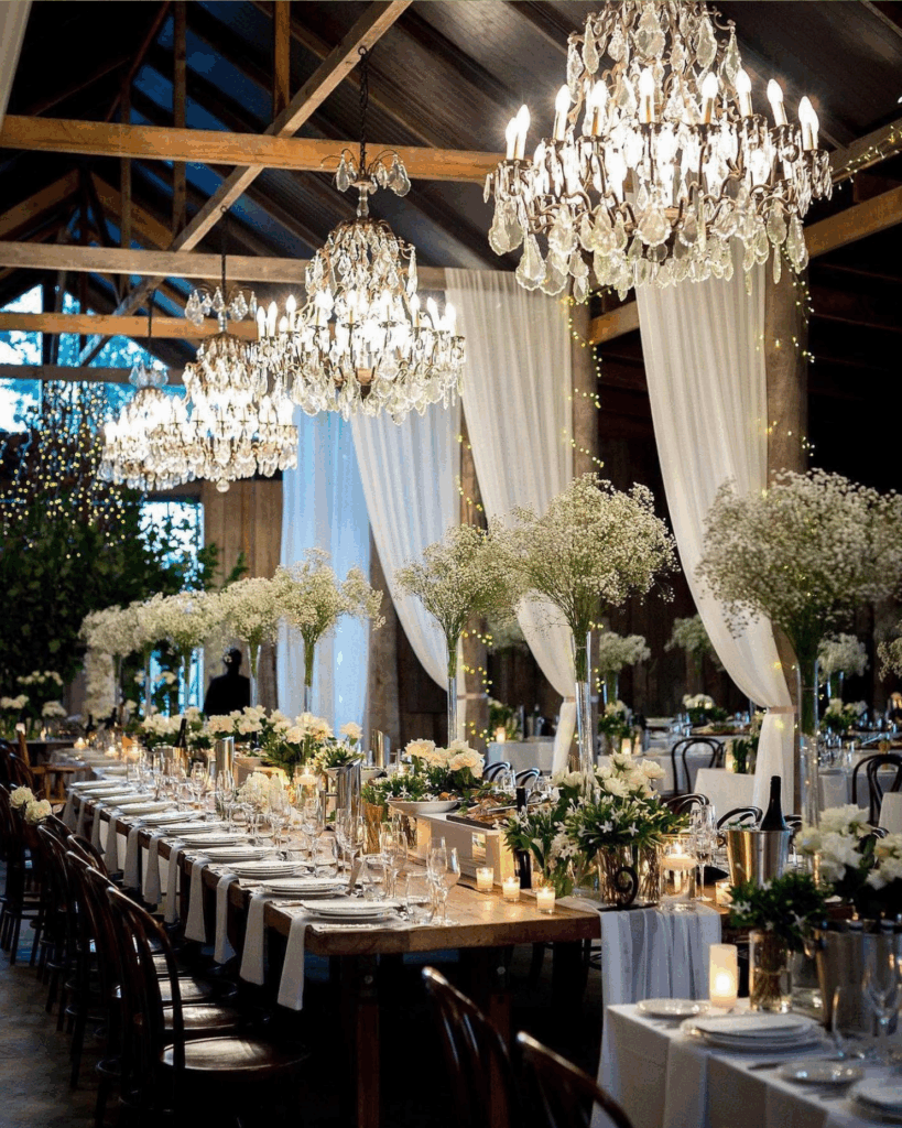 100 Breathtaking and Exclusive Australian Wedding Venues on every Couples Wish List! 23 Elegant indoor wedding reception at Anambah House featuring chandeliers, floral centerpieces, and a beautifully set long table surrounded by rustic decor.