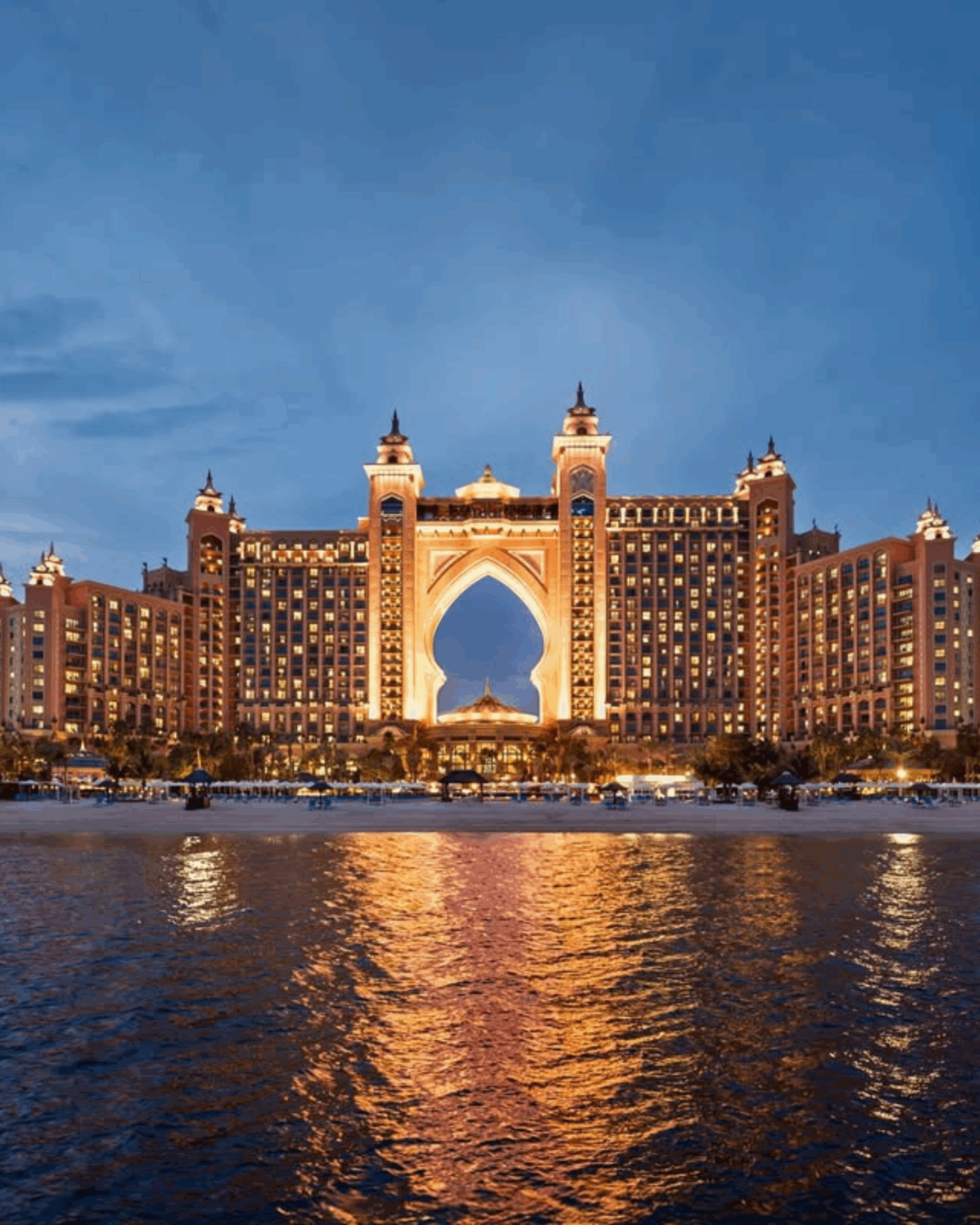 Atlantis The Palm hotel in Dubai, illuminated at dusk, reflecting on the water, a luxurious destination for weddings and events.