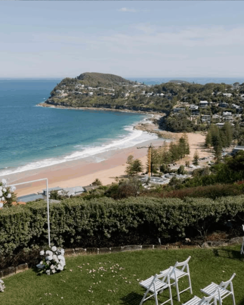 100 Breathtaking and Exclusive Australian Wedding Venues on every Couples Wish List! 8 Cliff-top garden at Jonah's Restaurant overlooking Whale Beach, featuring white chairs set for an intimate wedding ceremony, with lush greenery and stunning ocean views.