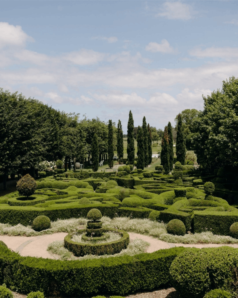 100 Breathtaking and Exclusive Australian Wedding Venues on every Couples Wish List! 9 Manicured European-style gardens at The Merribee in Numbaa, NSW, featuring lush hedges, circular topiary, and a scenic backdrop ideal for wedding ceremonies.