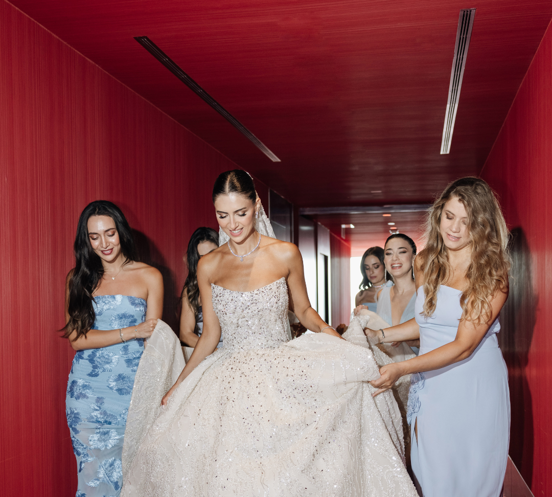 Bridal party assisting the bride in a sparkling wedding gown, showcasing friendship and elegance in a modern setting.